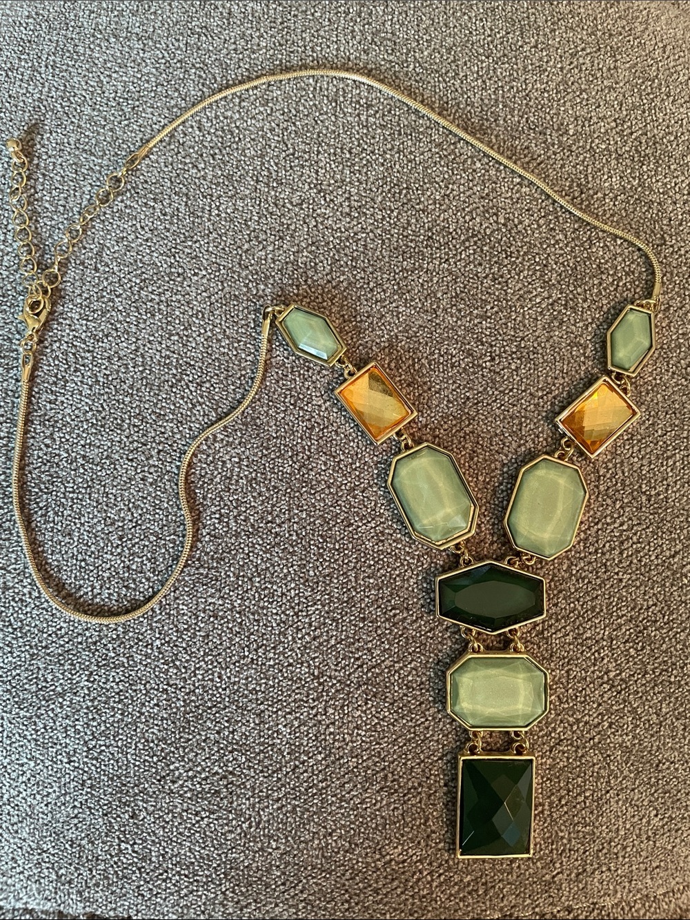 Gold chain necklace with green and topaz jewels.